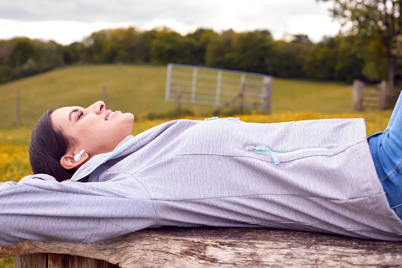 Una estudiante de oposiciones descansa escuchando música en la naturaleza
